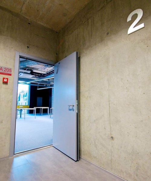 Blick in ein Klassenzimmer durch die offene Kamintür einer Schule mit Betonwänden