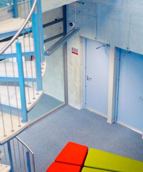 uddannelsesinstitution i beton med gr&aring; brandd&oslash;re